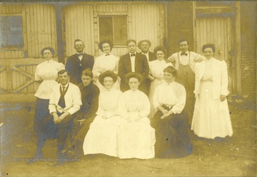 All of the persons in the photograph are unidentified, including the hotel. Possibly a Chesapeake &amp; Ohio  (C &amp; O) industrial style architecture in the background in Hinton. Inscribed on the back is "Purchased by Stephen Trail in Hinton West Virginia." 