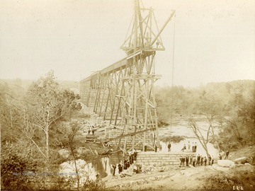 Several unidentified people stand near an abutment of a new bridge during the construction of the Ohio extension of the Norfolk &amp; Western Railroad. 