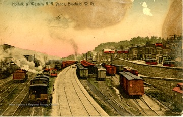 Postcard color image of the several tracks and cars. Part of the town can be seen on the right side.