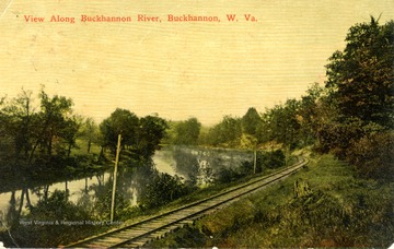 Color image postcard of the Buckhannon River running beside a railroad track in Upshur County.