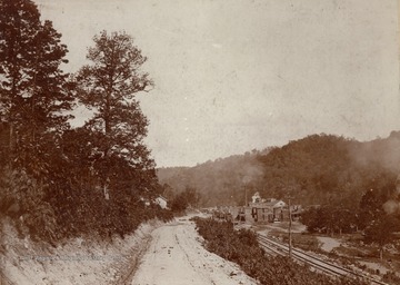 Small town located on the Gauley River and named for Senator Johnson Camden. A lumber yard can be seen the down a wheel-rutted dirt road next to the railroad tracks.