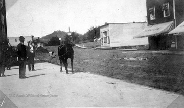 Unidentified man shows a horse on the sidewalk next to Elk Street in Gassaway.
