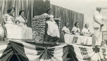 This is a photo of the Mason County Potato Festival Queen on her potato throne. The queen is surrounded by her court. The Potato Festival began August 1, 1938 to promote agriculture. All persons are unidentified. 