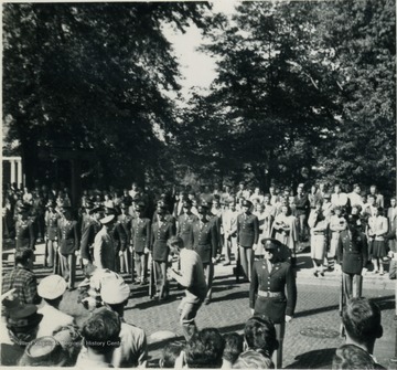 General Dwight D. Eisenhower (wearing a light color uniform, to the left of the photographer) reviews the members of West Virginia University's ROTC Units on campus. 