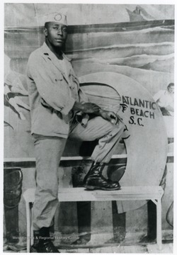 Boyd, wearing Army fatigues poses in front of mural labeled, "Atlantic Beach, S. C." Information with the photograph includes "Courtesy of Kitty Hughes". 