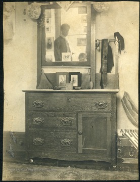 One of the furnishings in a dorm room was a dress/wash stand. Notice the reflection of an unidentified student in the mirror.