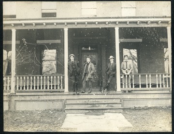 Unidentified students, one wearing a cadet uniform casually pose on the porch of Episcopal Hall. 