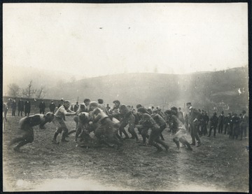Unidentified WVU students playing football. Very few are wearing helmets and padding.  