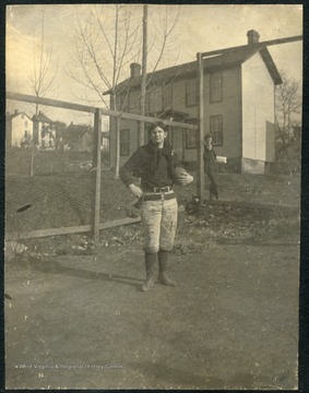 WVU student poses with a football, wearing a uniform with "E" &amp; "H" stamped on his pants, for "Episcopal Hall".