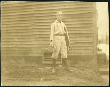 Unidentified student-athlete, probably a catcher, holding a mitt, mask and chest protector. 