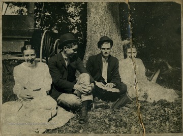 Group of friends pose outside, sitting under a tree.