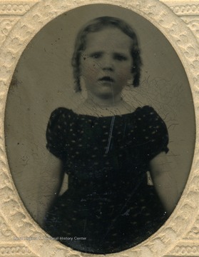 A young girl wearing rounded neckline and puffy, short sleeved dress, popular fashion for children in the mid 19th century.