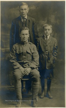Group portrait of three members of the Birchinal family. One is wearing an army uniform and the elderly man and young boy are standing.
