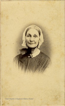 An older woman in a bonnet and polka dot dress. There is a revenue stamp on the back of the photograph indicating a tax was paid to support the Federal War effort during the Civil war. 