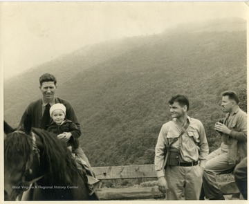 U. S. Forest Service guide, Jefferson Goldizen holds three year-old David Hunter Strother IV (great-grandson of "Porte Crayon") in the saddle as the boy's father, Porter Strother,(right)looks on. The dedication of a mountain peak as "Mt.Porte Crayon" in the Monongahela Forest was to honor the famous 19th century artist, writer, explorer, Civil War soldier, and diplomat, David Hunter Strother of Martinsburg, West Virginia.