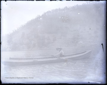 Unidentified boater rows on a river.