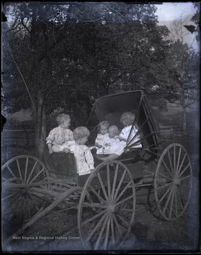 Four young children and one unhappy baby, all unidentified and dressed in their best bib and tucker, sit in an unhitched buggy.