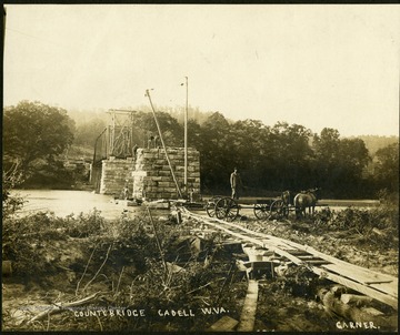 Unidentified workers building a bridge of iron and stone piers over the Cheat River in Preston County.