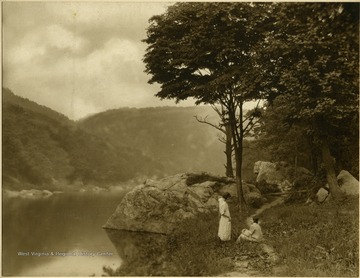 Two unidentified women relax on the river bank near Rockley, a small industrial village submerged when Cheat Lake was created.