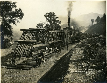 The Hurley lays the wooden ties as workers lay the rails. Location is in Western Maryland, possibly Allegany County.