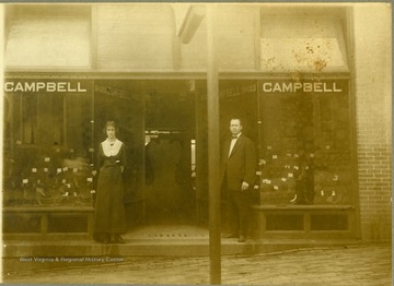 Most likely the couple is W. Benton and Edna Campbell, owners of the shoe store, posing in front of their business located at 318 Main Street in Fairmont.
