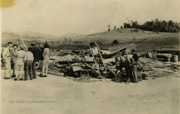People observe the ruins including a gas pump and cases of unbroken bottles of pop.