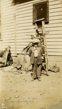 Small boy wearing his best suit of clothes, including a cap.