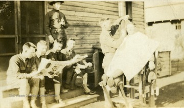 Men read while waiting their turn with the barber in a make-shift outside "shop". Many West Virginians trained at Camp Lee for fighting in Europe during World War I. Most were members of the 313th, 314th and 315th Field Artillery Units.