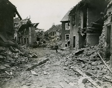 A lone soldier walks around the destroyed buildings in a German town towards the end of the war.