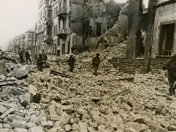 Information on the back of photo reads: "Infantrymen of the Fourth Armored Division, Third U.S. Army, advance through rubble in a battered street in Worms, Germany, as they clear out Nazi snipers in the captured city March 20, 1945. Worms is on the west bank of the Rhine River nine miles north of Ludwigshafen."