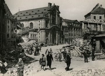 Information on back of photo reads: "Civilians move about on a street in a shell-torn Bamberg, Germany, after occupation of the city by troops of the Seventh U.S. Army April 14, 1945. Enemy forces withdrew from the medieval city, 30 miles northwest of Nurenberg, after a short fight. The retreating Nazis blew up the bridge across the Main and Renitz Rivers, leaving Bamberg an island."