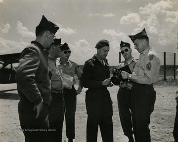 Raymond Young shows unidentified military personnel, including a Dutch Captain a K-20 camera. The military personel were part of a NATO (North Atlantic Treaty Organization) unit stationed in Europe.