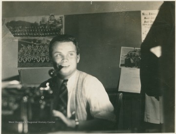 Bond sits at a typewriter with a pipe clinched in his teeth, at the Daily Athenaeum Office, the University's newspaper.  Bond subsequently became a Professor of Journalism at WVU.