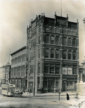 This photograph prominently features the Reilly building - now the site of the modern headquarters of WesBanco.  A prominent citizen with offices in this building was Millard F. Giesey (September 9, 1856 - December 22, 1931), a renowned architect. After five years of local study and apprenticeship, Giesey opened his office in 1886. For several years he was located in the Reilly Building at the corner of 14th and Market Streets in downtown Wheeling. Giesey practiced with Edward Bates Franzheim and sometimes Frederic F. Faris, a partnership which led the profession in West Virginia. During the 1890s, Giesey designed the Pocahontas County Court House, the Towers School in Clarksburg, and Ladies Hall, which is now Agnes Howard Hall, at West Virginia Wesleyan College in Buckhannon. In July 1899, he formed his partnership with Faris, and they maintained offices in Masonic Temple Building in Wheeling. One of the most famous designs by Giesey and Faris was the West Virginia Building, of Neoclassical Revival design, at the Louisiana Purchase Exposition in St. Louis in 1904.  Several of Giesey's buildings have been placed on the National Register of Historic Places, including the Pocahontas County Courthouse and Jail, the L. S. Good House in Wheeling, the War Memorial Building in Wetzel County, the Fayette County Court House, and the Warwood Fire Station. (WV Encyclopedia).