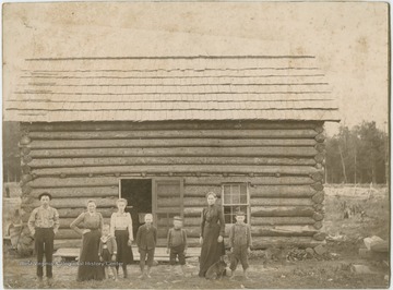 Probably the Joe Harr family outside of their log house. 