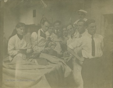 Med students during lab, hold up a cadaver for group portrait.