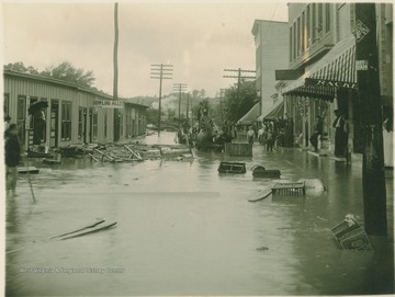 Debris floats through the street as a team of horses, hitched to a wagon, make their way in the water.