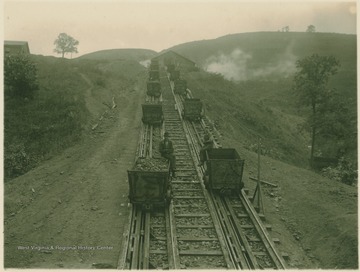 Two unidentified workers hitch a ride on cars running to and from a coal tipple