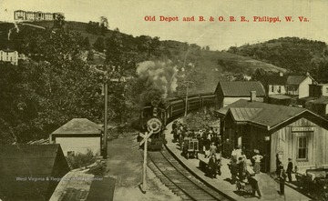 Travelers await train arriving at station in Philippi, West Virginia. Published by Reger News Stand. See original for correspondence. (From postcard collection legacy system.)