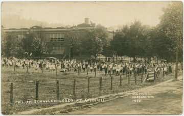 Students gather in the yard outside of school building for activity. (From postcard collection legacy system.)