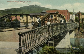 Illustrated postcard of two men and a boy standing along pedestrian walkway across bridge on Bridge Street. See original for correspondence. Published by Grant Graham. (From postcard collection legacy system.)