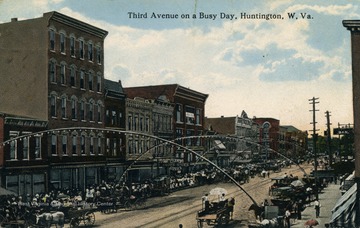 Streets are lined with people and horse and buggies as a busy day progresses in Huntington, West Virginia. See original for correspondence. (From postcard collection legacy system.)