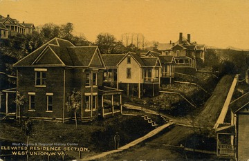 Paved road lined with houses. (From postcard collection legacy system.)