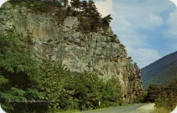 Caption on back of postcard reads: "On W. Va. Route 28 West of Petersburg, W. Va. in Grant County Wildcat Rock rising almost a hundred feet hangs out over half the highway. The highway is literally chiseled through the side of these rocks." Published by Naturecraft. (From postcard collection legacy system.)