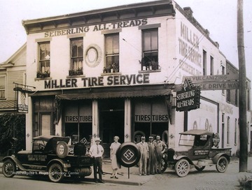 Promo vehicles, one displaying Miller Tire Service and the other Seiberling All Treads also parked outside of the store front.