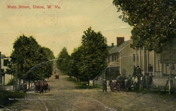 Men pose for the picture on the front porch of the Union Hotel on right. See original for correspondence. (From postcard collection legacy system.)