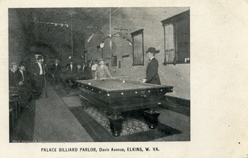 Interior view of group of men playing a game of billiards. See original for correspondence. (From postcard collection legacy system.)
