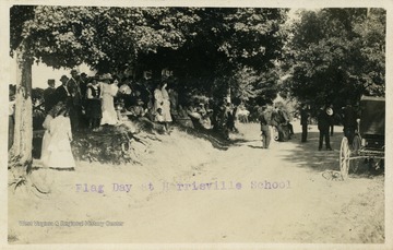 Students gather on road bank while people in the street hold a variety of instruments. (From postcard collection legacy system.)