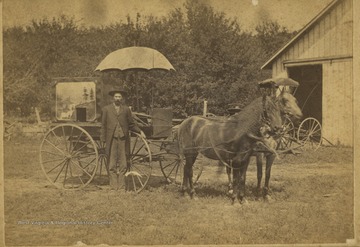 Unidentified photographer poses with his wagon and horses. A camera portal can be seen in the box housing the camera which is mounted on the wagon.  