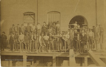 Caption included with the photograph, "At the Old Pump Station-- this crew of men is shown during construction of the old pump station on Cobun Creek. The man in suit and derby is Charles Miller. This building now houses Dinsmore Tire company. The picture was provided by Mrs. Jess Madigan of 416 Dorsey Avenue. The building was, and may still be, next to the City Water Plant on South University Avenue in Morgantown, W. Va. Reprinted in the 1963 Centennial Edition of the Morgantown Post."